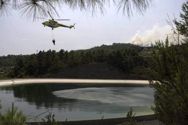 Požární helikoptéra doplňuje vodu | Foto: Reuters