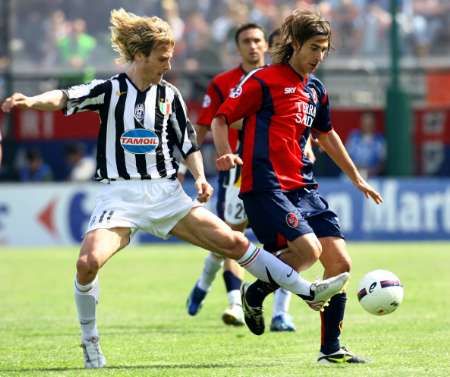 Pavel Nedvěd z Juventusu Turín v souboji s hráčem Cagliari Danielem Contim. | Foto: Reuters