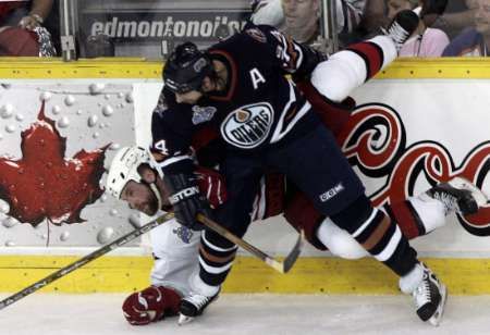 Edmontonský útočník Ryan Smyth (v nodrém) atakuje u hrazení Aarona Warda z Caroliny. | Foto: Reuters