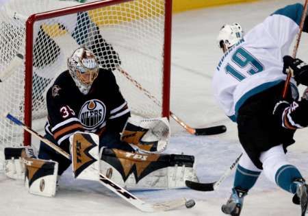 Brankář Edmontonu Oilers Dwayne Roloson zastavil pokus Joea Thorntona z týmu San Jose Sharks v zámořské NHL. | Foto: Reuters