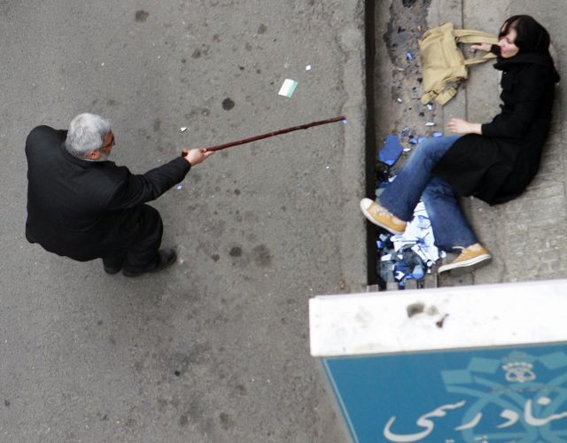 Policista v civilu hrozí demonstrantce, povalené na zem. | Foto: Reuters