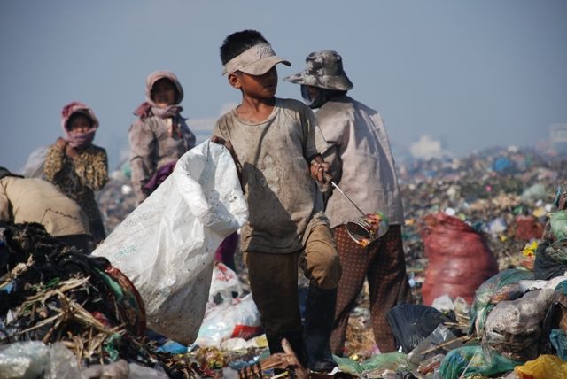 Kambodža - Sběr a recyklace odpadu zaměstnává přibližně 1 % městské populace rozvo­jových zemí, tedy více než 15 milionů lidí.  Jen v Číně pracuje téměř 6 milionů sběračů odpadu, v Indii milion. Odpad dává obživu také stovkám lidí na největší kambodžské skládce na předměstí hlavního města Phnom Penh.  Podle UNICEF pracuje v Kambodži 45 % dětí, část z nich právě tady. Děti se bosy, nebo jen v "žabkách" brodí odpadem všeho druhu: hnijícími zbytky z trhu, střepy skla nebo kovu, chemikáliemi z dílen nebo infekčním odpadem z nemocnic, včetně injekčních stříkaček a jehel. Bodné i řezné rány na nohou jsou jejich běžnou zkušeností, stejně jako střevní a kožní problémy nebo dokonce tetanus.  Vytříděný odpad je spalován přímo na skládce, toxický kouř vdechují děti i dospělí. Hladiny těžkých kovů, které kolují v tělech sběračů a v mateřském mléce místních žen, překračují maximální povolené hladiny sto- až tisícinásobně. | Foto: Markéta Kutilová / Člověk v tísni