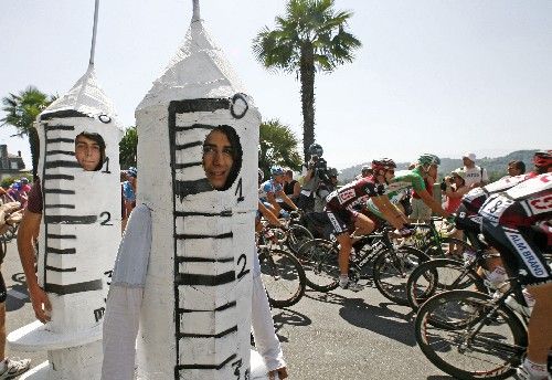 Peloton Tour de France projíždí kolem diváků převlečených za injekční stříkačky. | Foto: Reuters