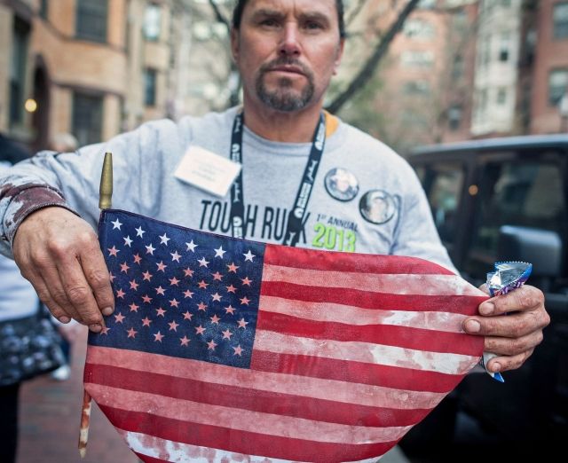 Muž drží v rukou zakrvácenou vlajku USA, kterou nalezl na místě výbuchu. | Foto: ČTK