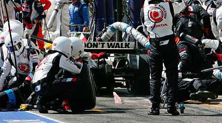 Jenson Button předčasně vyjíždí z boxů a tankovací hadicí sráží mechaniky. | Foto: Reuters