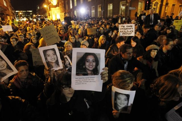 Protestors outside Leinster House in Dublin Wednesday Nov. 14, 2012 against the death in October of Savita Halappanavar, pictured, a dentist aged 31, who was 17 weeks pregnant, after suffering a miscarriage and septicaemia. The woman's husband Praveen Halappanavar claims she had complained of being in agonising pain while in Galway University Hospital. He has said that doctors refused to carry out a medical termination because the foetus's heartbeat was present. Ireland's constitution officially bans abortion, but a 1992 Supreme Court ruling found the procedure should be legalized for situations when the woman's life is at risk from continuing the pregnancy. (AP Photo/ Julien Behal, PA | Foto: ČTK