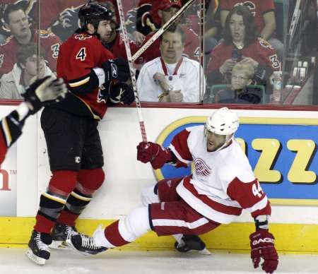 Obránce Calgary Roman Hamrlík sráží útočníka Detroitu Todda Bertuzziho. | Foto: Reuters