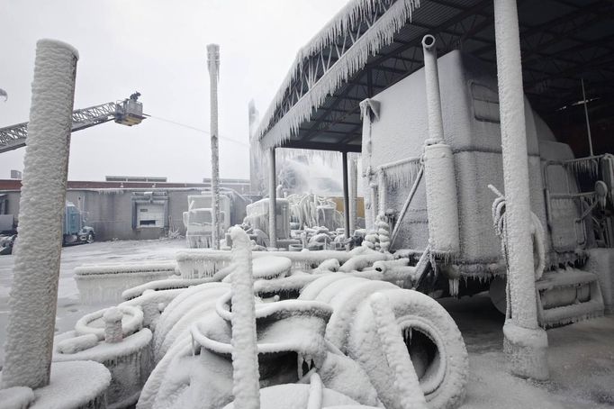 Ice-covered trucks are blanketed in smoke after a warehouse fire in Chicago January 23, 2013. Fire department officials said it is the biggest fire the department has had to battle in years and one-third of all Chicago firefighters were on the scene at one point or another trying to put out the flames. An Arctic blast continues to grip the U.S. Midwest and Northeast Wednesday, with at least three deaths linked to the frigid weather, and fierce winds made some locations feel as cold as 50 degrees below zero Fahrenheit. (minus 46 degrees Celsius). REUTERS/John Gress (UNITED STATES - Tags: DISASTER ENVIRONMENT) Published: Led. 23, 2013, 6 odp.