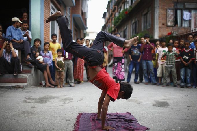 People watch as Drumpal Choudhary, 11, a street performer, performs his tricks on a street in Kathmandu August 15, 2012. Drumpal and his siblings Shivani and Gchan, who came to Kathmandu from India 5 years ago, earn their living by performing tricks on the streets of Kathmandu. According to Drumpal they earn around $10 a day by performing tricks, which is not enough to feed their 10-member family living together in a small hut without a proper toilet or any basic needs. REUTERS/Navesh Chitrakar (NEPAL - Tags: SOCIETY POVERTY IMMIGRATION) Published: Srp. 15, 2012, 4:38 odp.