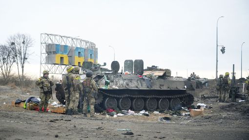 Ukrajinští vojáci stojí na stráži u zničeného obrněného vozidla na předměstí Charkova na Ukrajině 25. února 2022.