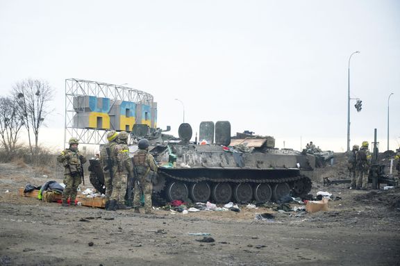 Ukrajinští vojáci stojí na stráži u zničeného obrněného vozidla na předměstí Charkova na Ukrajině 25. února 2022.