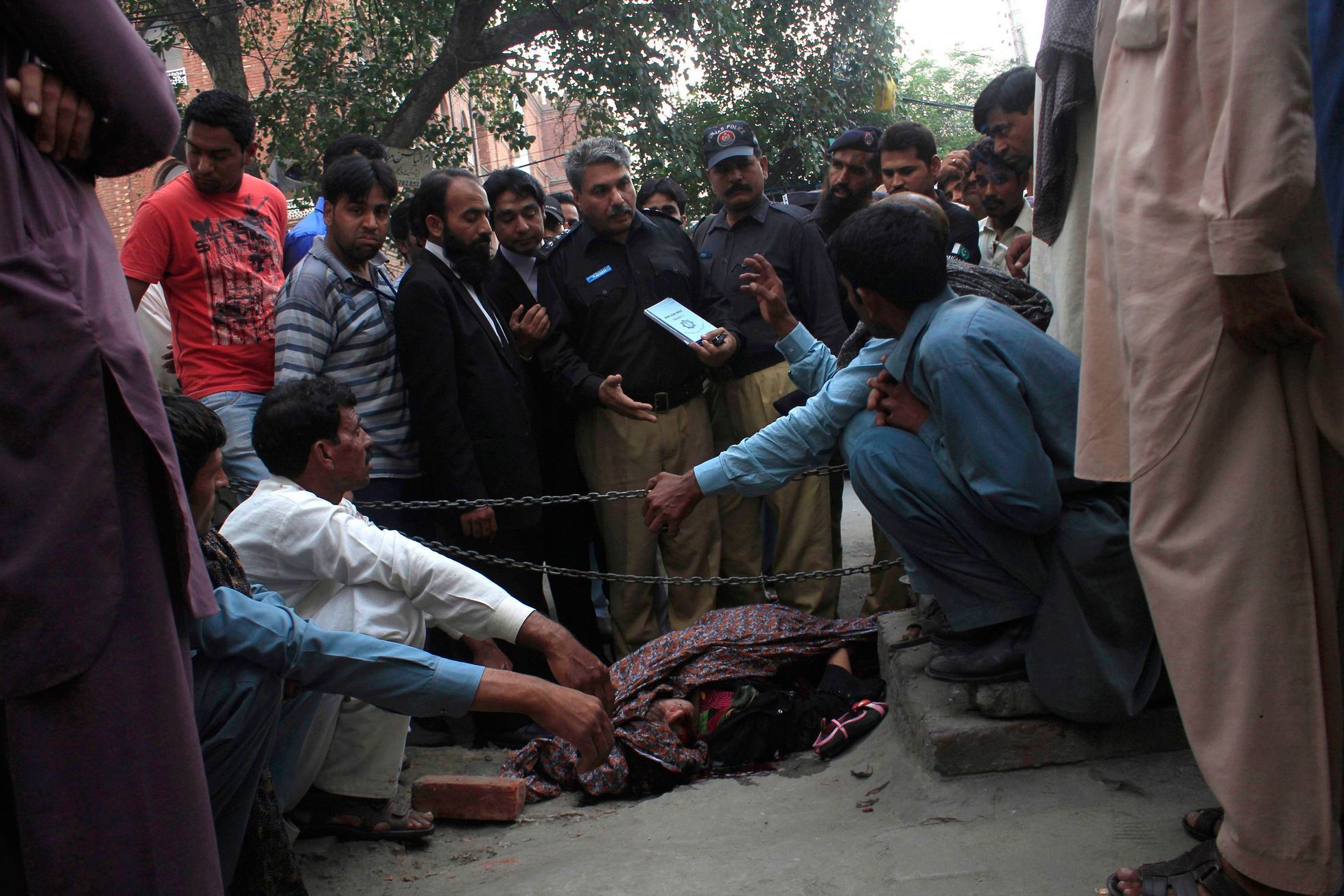 File photo of police collecting evidence near the body of Iqbal, who was killed by family members, at the site near the Lahore High Court building in Lahore file photo