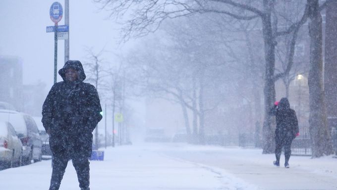 Žena v Bostonu čeká na autobus během sněhové bouře na východě USA.