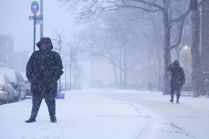 Žena v Bostonu čeká na autobus během sněhové bouře na východě USA.