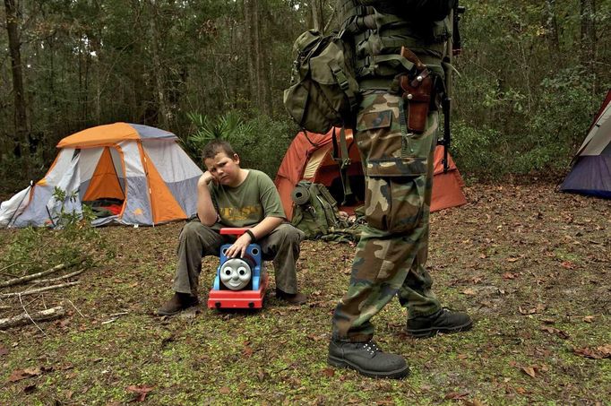 A young boy sits on a child's toy and sulks because his sister got to carry the rifle that he wanted to carry as members of the North Florida Survival Group gather for a field training exercise in Old Town, Florida, December 8, 2012.The group trains children and adults alike to handle weapons and survive in the wild. The group passionately supports the right of U.S. citizens to bear arms and its website states that it aims to teach "patriots to survive in order to protect and defend our Constitution against all enemy threats". Picture taken December 8, 2013. REUTERS/Brian Blanco (UNITED STATES - Tags: SOCIETY POLITICS) ATTENTION EDITORS: PICTURE 18 OF 20 FOR PACKAGE 'TRAINING CHILD SURVIVALISTS' SEARCH 'FLORIDA SURVIVAL' FOR ALL IMAGES Published: Úno. 22, 2013, 1:01 odp.