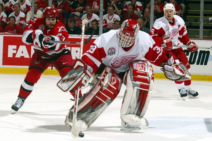 Brankář Detroitu Dominik Hašek kryje puk před útočníkem Caroliny Martinem Gelinasem.