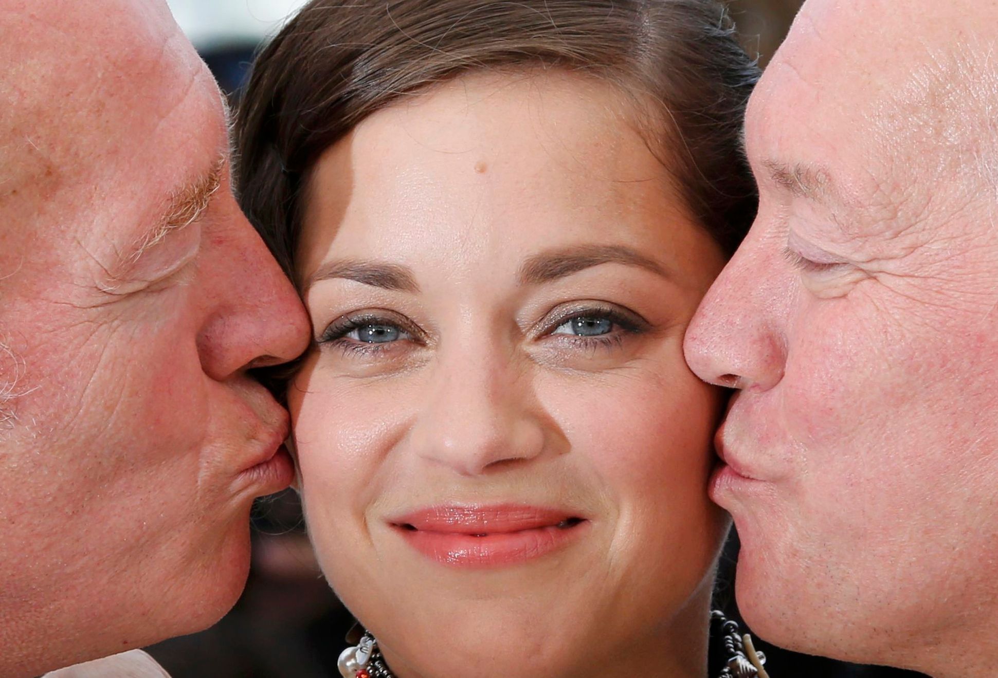 Directors Jean-Pierre and Luc Dardenne kiss cast member Marion Cotillard as they pose during a photocall for the film &quot;Deux jours, une nuit&quot; in competition at the 67th Cannes Film Festival i