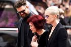 Sharon Osbourneová s dětmi Kelly a Jackem kráčí v čele průvodu, zatímco stovky lidí vzdávají poslední sbohem ikoně světové hudby. Silný lidský moment soucitu a rodinné soudržnosti.
