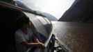 A woman looks at the Yangtze River as she stands onboard a boat near Badong, 100km (62 miles) from the Three Gorges dam in Hubei province in this August 7, 2012 file photo. China relocated 1.3 million people during the 17 years it took to complete the Three Gorges dam. Even after finishing the $59 billion project last month, the threat of landslides along the dam's banks will force tens of thousands to move again. It's a reminder of the social and environmental challenges that have dogged the world's largest hydroelectric project. While there has been little protest among residents who will be relocated a second time, the environmental fallout over other big investments in China has become a hot-button issue ahead of a leadership transition this year. Picture taken on August 7, 2012. To match story CHINA-THREEGORGES/ REUTERS/Carlos Barria/Files (CHINA - Tags: POLITICS ENVIRONMENT BUSINESS ENERGY) Published: Srp. 22, 2012, 8:46 odp.