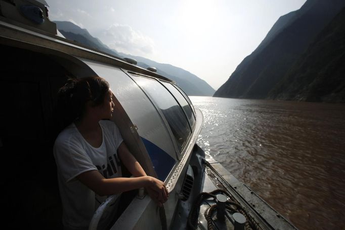 A woman looks at the Yangtze River as she stands onboard a boat near Badong, 100km (62 miles) from the Three Gorges dam in Hubei province in this August 7, 2012 file photo. China relocated 1.3 million people during the 17 years it took to complete the Three Gorges dam. Even after finishing the $59 billion project last month, the threat of landslides along the dam's banks will force tens of thousands to move again. It's a reminder of the social and environmental challenges that have dogged the world's largest hydroelectric project. While there has been little protest among residents who will be relocated a second time, the environmental fallout over other big investments in China has become a hot-button issue ahead of a leadership transition this year. Picture taken on August 7, 2012. To match story CHINA-THREEGORGES/ REUTERS/Carlos Barria/Files (CHINA - Tags: POLITICS ENVIRONMENT BUSINESS ENERGY) Published: Srp. 22, 2012, 8:46 odp.