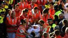 An injured runner is led away by medics following the sixth running of the bulls at the San Fermin festival in Pamplona July 12, 2012. Several runners suffered light injuries in a run that lasted two minutes and twenty seconds, according to local media. REUTERS/Eloy Alonso (SPAIN - Tags: ANIMALS SOCIETY) Published: Čec. 12, 2012, 8:11 dop.