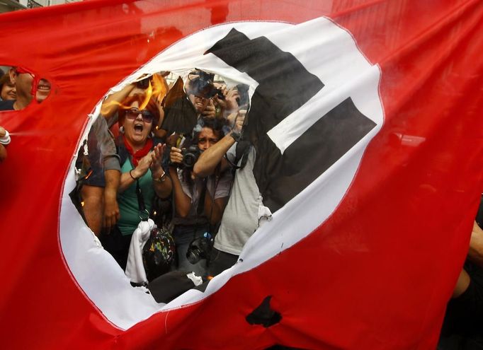 Demonstrators burn a flag emblazoned with a swastika during a demonstration against the visit of German Chancellor Angela Merkel in central Athens, October 9, 2012. Germany's Angela Merkel arrived in Greece on her first visit since Europe's debt crisis erupted here three years ago, braving protests to deliver a message of support - but no new money - to a nation hammered by recession and fighting to stay in the euro. REUTERS/Yannis Behrakis (GREECE - Tags: POLITICS BUSINESS TPX IMAGES OF THE DAY) Published: Říj. 9, 2012, 11:47 dop.