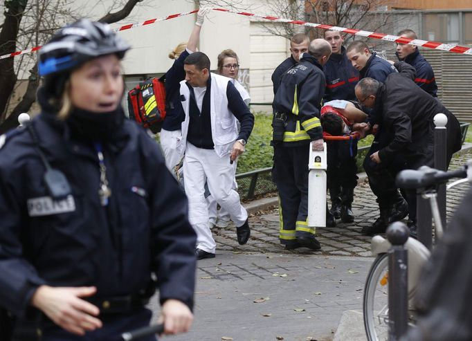 Hasiči vynášejí jednoho z lidí, kteří byli zraněni při střelbě v pařížské redakci týdeníku Charlie Hebdo.