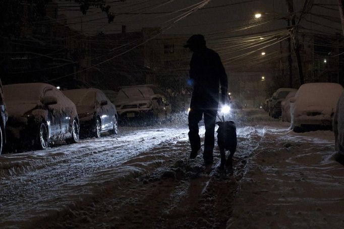 A man walks with his dog in the snow during the nor'easter, also known as a northeaster storm, in Jersey City, New Jersey November 7, 2012. A wintry storm dropped snow and rain on the U.S. Northeast on Wednesday, bringing dangerous winds and knocking out power in a region where hundreds of thousands were still in the dark after Superstorm Sandy. REUTERS/Eduardo Munoz (UNITED STATES - Tags: DISASTER ENVIRONMENT)