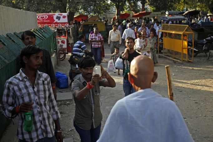 A man takes a photo as Mahesh Chaturvedi (backfacing), 63, who dresses up like Mahatma Gandhi, walks on the streets of New Delhi September 28, 2012. Chaturvedi says that the soul of Gandhi resides in him and he has been sent to continue the work of Father of the Nation. After his self proclaimed transformation in 2002 as Gandhi, Chaturvedi has been travelling extensively and plays up to his startling resemblance to Gandhi at protests and demonstrations. Picture taken September 28, 2012. REUTERS/Mansi Thapliyal (INDIA - Tags: SOCIETY) Published: Lis. 26, 2012, 3:59 dop.