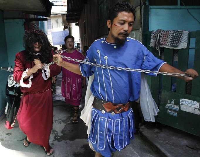 Felix Anaye, 32, who is portraying Jesus Christ, walks as he is pulled on a chain by a man portraying a Roman soldier ahead of Good Friday in Mandaluyong city, metro Manila March 28, 2013. Penitents will be nailed to a cross on Good Friday in a display of religious devotion in the Philippines, a predominantly Catholic country. Holy Week is celebrated in many Christian traditions during the week before Easter. REUTERS/Romeo Ranoco (PHILIPPINES - Tags: RELIGION) Published: Bře. 28, 2013, 6:02 dop.