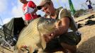 A 6.73 kg carp is held by Tony Darnand of France during the 14th Carpfishing World Championship in Corbu village, 310 km (192 miles) east of Bucharest, September 29, 2012. REUTERS/Radu Sigheti (ROMANIA - Tags: SOCIETY) Published: Zář. 29, 2012, 4:32 odp.