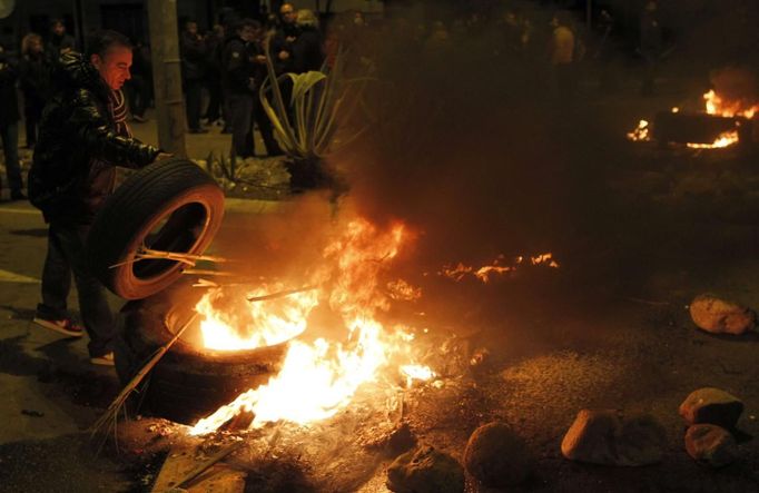 A man throws a tyre on another burning tyre, which is blocking an entrance of Mercabarna (wholesale market) at Zona Franca, in Barcelona November 14, 2012. Spain's two largest labour unions have called for a general strike on November 14, the second against the conservative government since they took power in December and coinciding with industrial action in Portugal on the same day. REUTERS/Albert Gea (SPAIN - Tags: BUSINESS EMPLOYMENT POLITICS CIVIL UNREST) Published: Lis. 14, 2012, 1:12 dop.