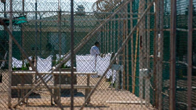 Za ploty a ostnatými dráty je vidět jeden z vězňů guantánamské věznice.