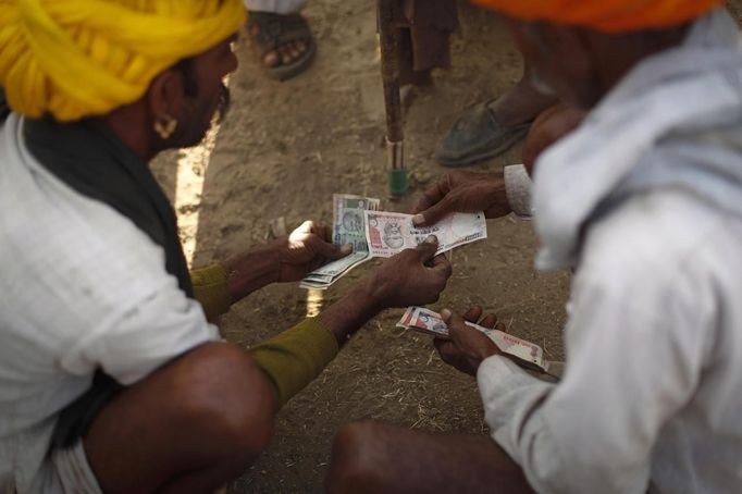 Camel herders count money at Pushkar Fair in the desert Indian state of Rajasthan November 23, 2012. Many international and domestic tourists throng to Pushkar to witness one of the most colourful and popular fairs in India. Thousands of animals, mainly camels, are brought to the fair to be sold and traded. REUTERS/Danish Siddiqui (INDIA - Tags: SOCIETY ANIMALS) Published: Lis. 23, 2012, 8:11 dop.