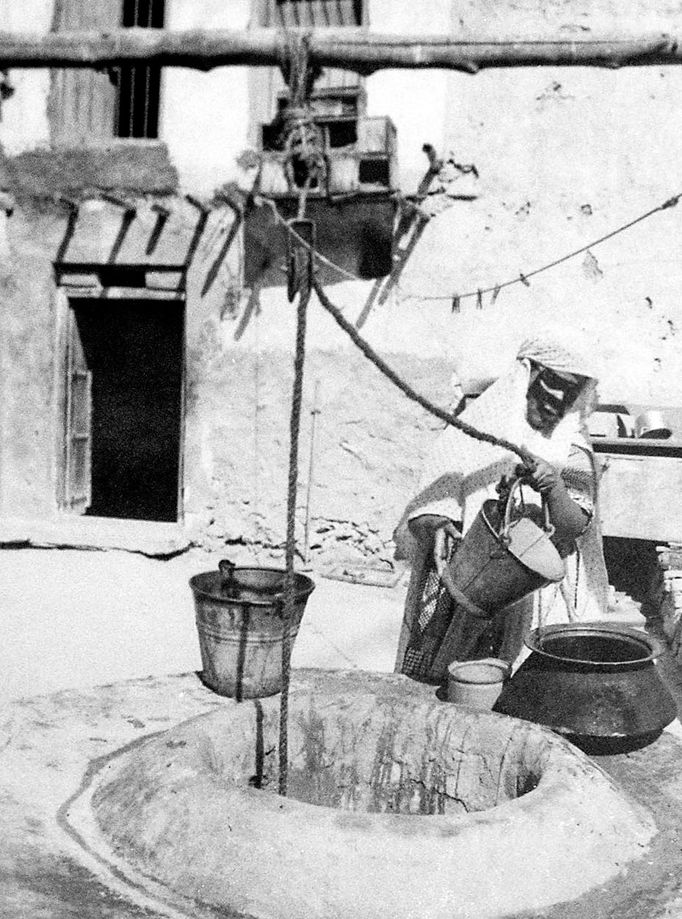 Žena plní nádoby s vodou u studně v Dauhá v Kataru v roce 1955. Fotografie ze země, která v roce 2022 bude pořádat mistrovství světa ve fotbale.