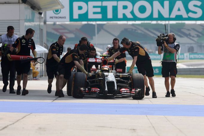 Mechanics push the car of Lotus Formula One driver Pastor Maldonado of Venezuela down the pit lane during the first practice session of the Malaysian F1 Grand Prix at Sep