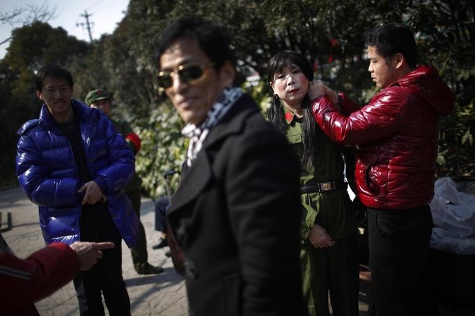 Xiao Cao (2nd R), a 57-year-old gay man, prepares for his dance performance with the help of his friends at Manxi park in Shanghai February 19, 2012. China's gay community has long been on the edges of society but it is gradually becoming more accepted. Cao, who is an unemployed drag queen, is one whose life lifts the curtain on a less romanticised view of Chinese homosexuals. Living in an eight-square-metre apartment behind a public toilet and with a monthly income of 500 yuan ($79) from social insurance, he passes his days dancing in public and spending time with friends at gay clubs. Picture taken February 19, 2012. REUTERS/Aly Song (CHINA - Tags: SOCIETY) CHINA OUT. NO COMMERCIAL OR EDITORIAL SALES IN CHINA. ATTENTION EDITORS PICTURE 12 OF 28 OF PACKAGE 'GAY AND OUT IN CHINA' TO FIND ALL IMAGES SEARCH 'GAY OUT CHINA' Published: Čer. 1, 2012, 12:38 dop.