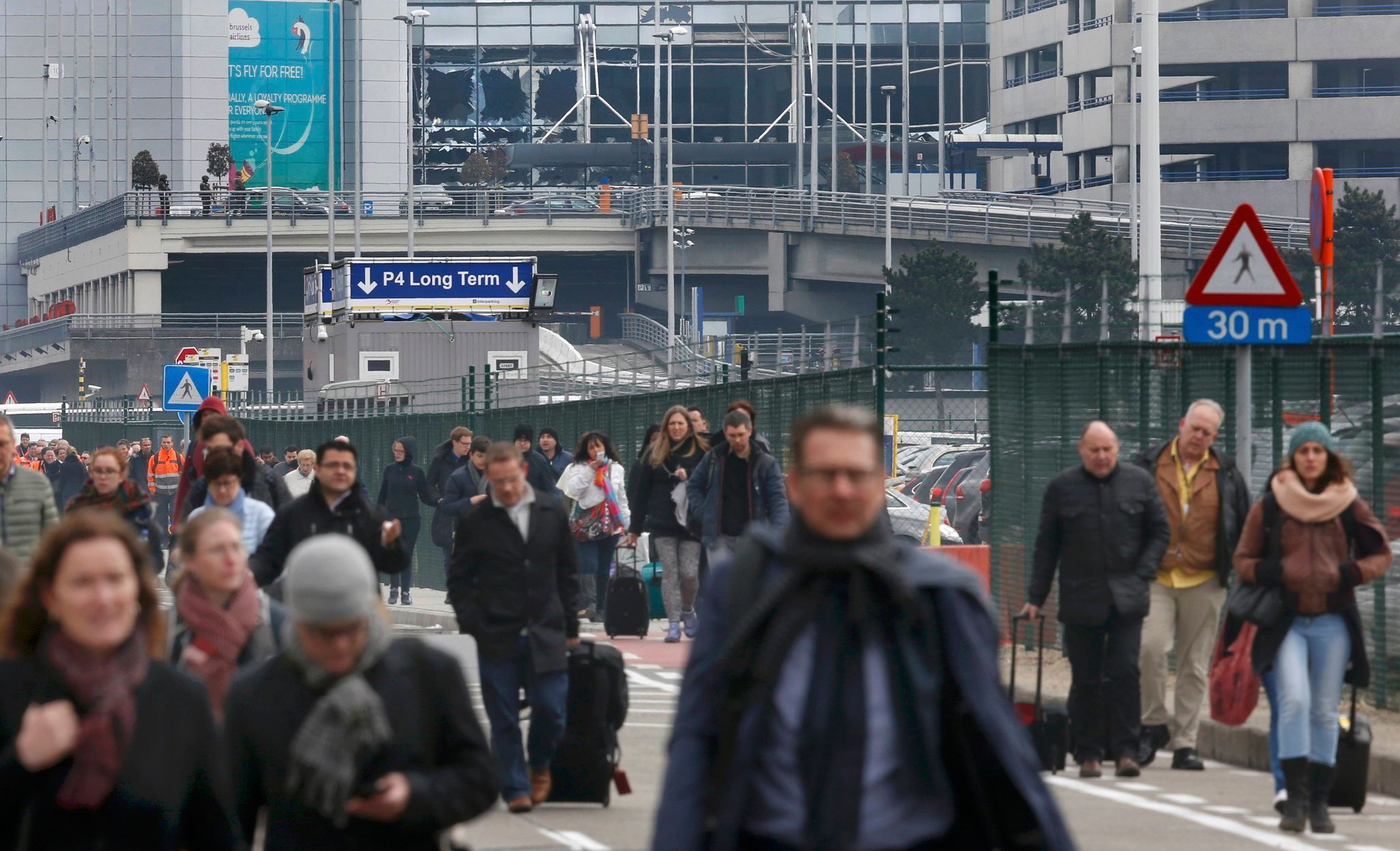 People leave the scene of explosions at Zaventem airport near Brussels, Belgium