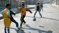 Iráčtí chlapci v prázdné ulici města Mosul hrají fotbal.