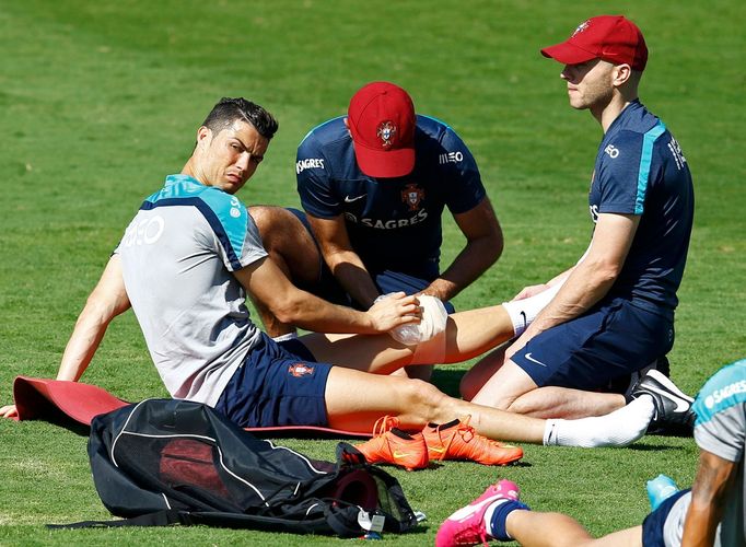 Portugal's Cristiano Ronaldo has his leg checked by team staff during an open training session in Campinas, June 18, 2014. Portugal is preparing to play the USA for Group