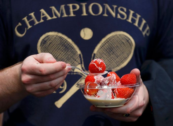 A spectator eats strawberries and cream at the Wimbledon Tennis Championships, in London June 26, 2013. REUTERS/Suzanne Plunkett (BRITAIN - Tags: SPORT TENNIS)