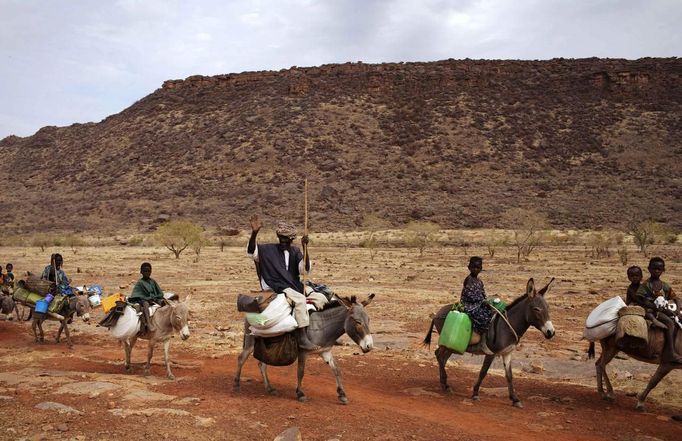 A farmer waves while riding a donkey with his family near Douentza January 28, 2013. REUTERS/Joe Penney (MALI - Tags: CIVIL UNREST POLITICS CONFLICT SOCIETY) Published: Led. 28, 2013, 8:39 odp.