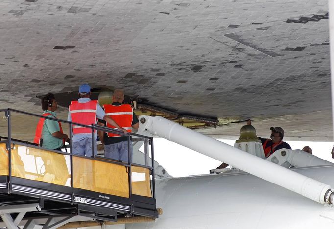 Space center workers work to attach space shuttle Discovery to a NASA 747 aircraft in the Mate Demate facility at Kennedy Space Center in Cape Canaveral