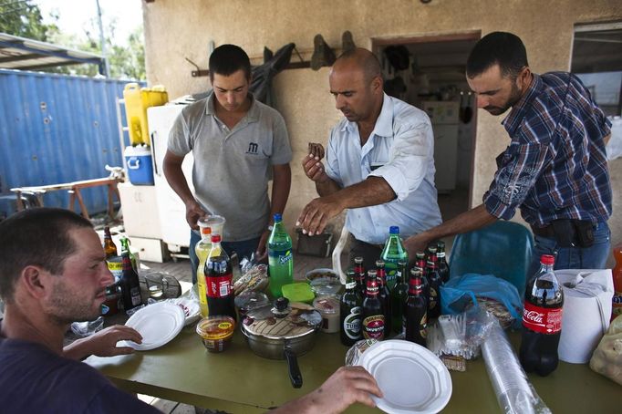 Nadav (C), the chief cowboy of the Yonatan herd, and his team eat at the end of the day after selling their cattle, just outside Moshav Yonatan, a collective farming community, about 2 km (1 mile) south of the ceasefire line between Israel and Syria in the Golan Heights May 21, 2013. Cowboys, who have been running the ranch on the Golan's volcanic rocky plateau for some 35 years, also host the Israeli military, who use half of the cattle farm, 20,000 dunams (5,000 acres), as a live-fire training zone. Israel captured the Golan Heights from Syria in the 1967 Middle East war and annexed the territory in 1981, a move not recognized internationally. Picture taken May 21, 2013. REUTERS/Nir Elias (ENVIRONMENT ANIMALS SOCIETY) ATTENTION EDITORS: PICTURE 23 OF 27 FOR PACKAGE 'COWBOYS OF THE GOLAN HEIGHTS' SEARCH 'COWBOY GOLAN' FOR ALL IMAGES Published: Kvě. 29, 2013, 10:08 dop.