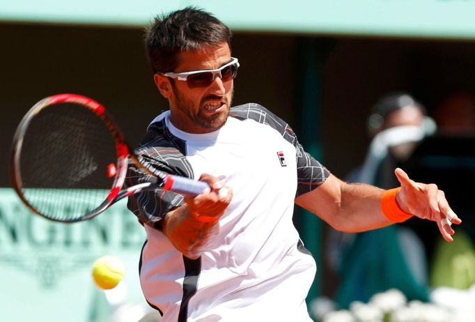 Srbský tenista Janko Tipsarevič odráží míček proti Francouzi Julienu Benneteau ve 3. kole French Open 2012.