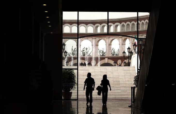 A man and a woman walk through a building that resembles a Roman Coliseum at the Florentia Village in the district of Wuqing, located on the outskirts of the city of Tianjin June 13, 2012. The shopping center, which covers an area of some 200,000 square meters, was constructed on a former corn field at an estimated cost of US$220 million and copies old Italian-style architecture with Florentine arcades, a grand canal, bridges, and a Coliseum-like building. REUTERS/David Gray (CHINA - Tags: SOCIETY BUSINESS) Published: Čer. 13, 2012, 5:48 odp.