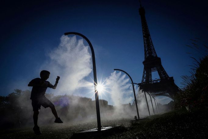 A boy plays under a spray of cooling water on a hot day outside the Eiffel Tower Stadium during the 2024 Olympics in Paris, France, July 28, 2024. REUTERS/Esa Alexander