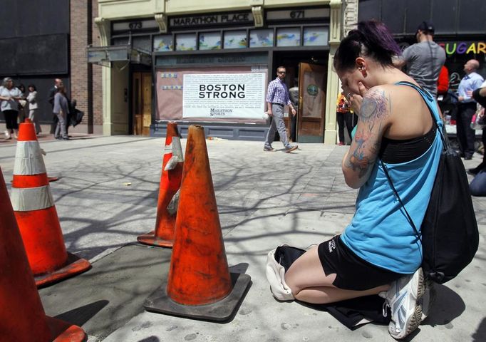 Hillary Branyik, 22, of Boston kneels at the site of the first explosion on Boylston Street after the street reopened to the public for the first time since the Boston Marathon bombings in Boston, Massachusetts April 24, 2013. U.S. officials say ethnic Chechen brothers, Tamerlan and Dzhokhar Tsarnaev, planted and detonated two pressure-cooker bombs near the finish line of the Boston Marathon on April 15, killing three people and injuring 264. Ten people lost limbs in the bombing. REUTERS/Jessica Rinaldi (UNITED STATES - Tags: CRIME LAW CIVIL UNREST) Published: Dub. 24, 2013, 5:48 odp.