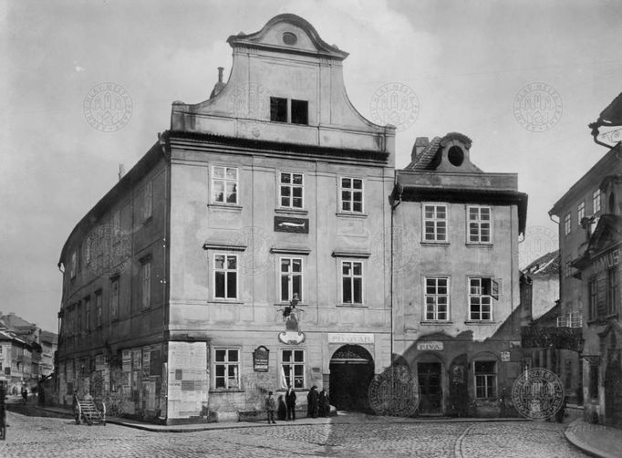 Pohled na domy (zleva) čp. 705 ("U Zlaté štiky") a 704 ("U Zlaté krávy") na nároží ulic Dlouhé (vlevo) a Masné na Starém Městě před zbořením v roce 1912.