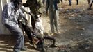 Men remove the burnt body of boy killed in an air strike by the Sudanese air force in a market in Rubkona